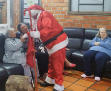 Papai Noel cumprimentando idosas no sofá do lar
