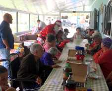 Papai Noel cumprimentando idosos do lar na mesa de refeição 
