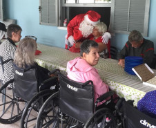 Papai Noel cumprimentando idosos do lar na mesa de refeição 