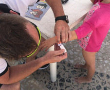 Policial da PCPR colocando pulseira de identificação em criança