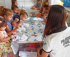 Policial civil orienta diversas crianças a colorir desenhos