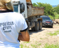 Policial civil observa caminhão com viatura estacionada logo atrás do veículo