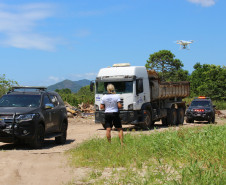 Policial civil observa caminhão entre duas viaturas