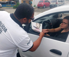 Policial civil entregando panfleto sobre dengue para motorista