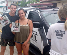 Dois veranistas exibindo panfletos sobre dengue, entregues pela polícia civil