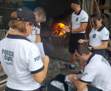 Vários policiais civis preparando as drogas para incineração