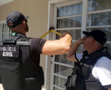 Policiais civis arrombando porta para investigação do local