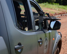 Policial civil em viatura, apontando fuzil