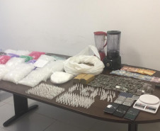 Drogas e demais produtos ilícitos apreendidos estão sobre mesa da delegacia