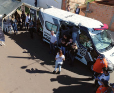 Imagem aérea mostrando policiais civis e demais pessoas junto ao veículo da PCPR