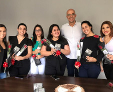 Seis mulheres segurando rosas vermelhas posando para foto junto ao delegado