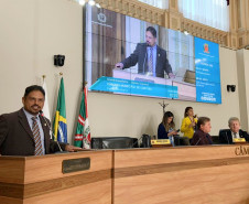 Homenageado discursando co m telão em segundo plano