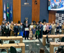 Delegado segurando o diploma junto aos participantes, posando para foto