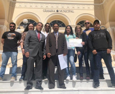 Homenageado e demais participantes posando para foto em frente à Câmara