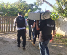 Policiais civis levando computador apreendido