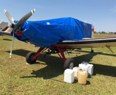 Avião apreendido, coberto com capa e alguns galões ao lado