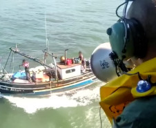 Policial civil em helicóptero alertando pescadores com megafone