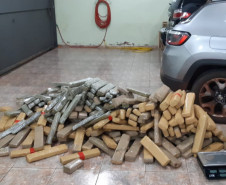 Diversos tabletes de droga e uma balança, ao lado de veículo