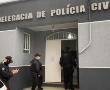 Três policiais civis entrando na delegacia