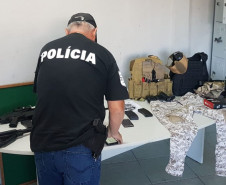 Policial civil organizando sobre uma mesa o material apreendido