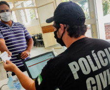 Policial civil consultando carteira de vacinação
