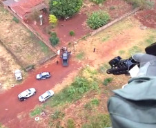 Policial civil em helicóptero acompanhando operação de policiais em terra
