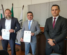 Delegado-geral e superintendente da CGU apresentando documento assinado. Junto, chefe da divisão de combate à corrupção.