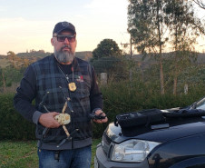 Investigador Fabiano Teixeira segurando drone ao lado de veículo