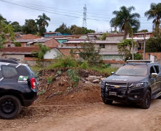 Duas viaturas da polícia civil circulando em rua de terra