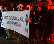Policiais civis segurando faixa homenageando os profissionais da saúde