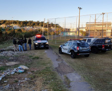 Vários policiais civis ao  lado de três viaturas.