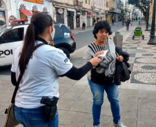 Policial civil entregando máscara para transeunte