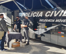 Homem recebe máscara em barraca da PCPR montada ao lado de ônibus da instituição