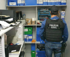 Policial civil observa estante com arquivos