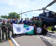 Integrantes do GOA segurando bandeiras, junto a helicóptero