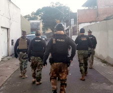 Vários policiais andando na rua, em frente ao local