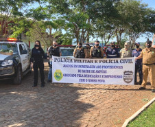 Policiais civis, bombeiros e policiais militares segurando uma faixa com homenagem