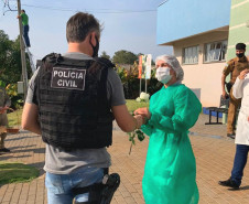 Policial civil entregando uma flor a uma profissional da saúde