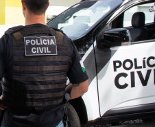 Policial civil ao lado de viatura