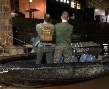 Policiais de costas, dentro do barco