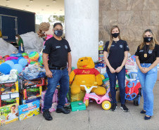 Policiais civis posando para foto junto a brinquedos doados