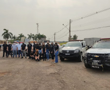 Policiais civis envolvidos no evento posando para foto ao lado de duas viaturas