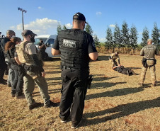 Policiais civis em pé observando  técnicas de algemamento