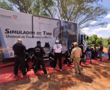 Policiais civis observam técnicas de algemamento, ao lado de caminhão simulador de tiro