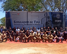 Alunos e instrutores posando para fotografia. Ao fundo, caminhão simulador de tiro