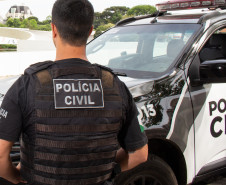 Policial civil ao lado de viatura