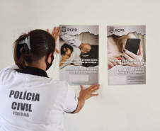 Policial civil fixando cartaz na parede