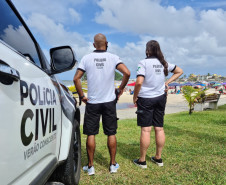 Dois policiais ao lado de viatura observam movimento no litoral