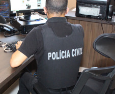 Policial civil de costas, ao computador