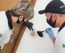 Policiais civis identificando digitais em um interruptor de energia